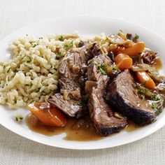 a white plate topped with meat, rice and veggies on top of a table