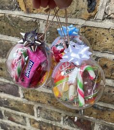 two clear glass ornaments with candy and candies in them hanging on a brick wall