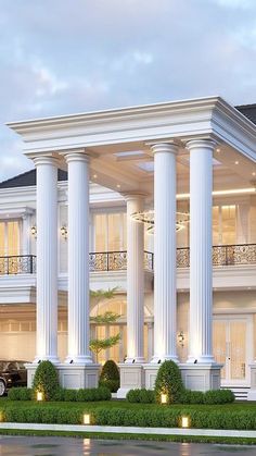 a large white house with columns and pillars on the front lawn at dusk, surrounded by greenery