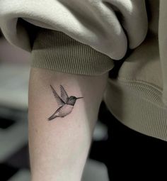 a small hummingbird tattoo on the left inner arm and leg, with black ink