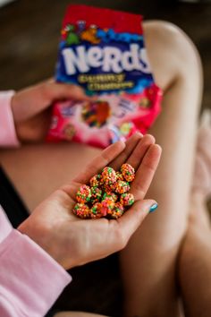 a person holding candy in their hand with a bag of nerds on the other side