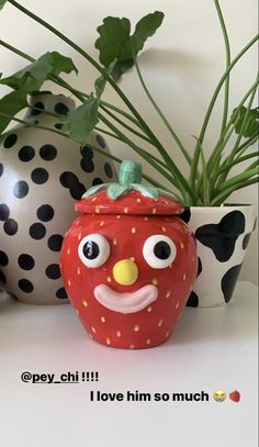 a potted plant with a face painted on it next to polka dot vases