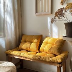 a wooden bench sitting in front of a window next to a vase with flowers on it