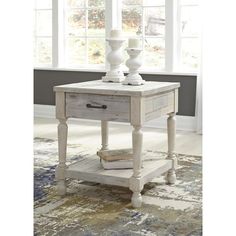 a white table with two vases on top and a rug in front of it