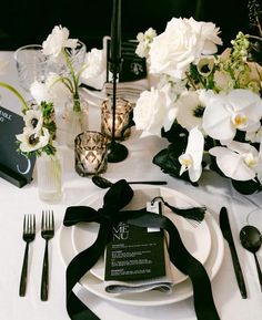 the table is set with white flowers and black napkins, which are tied together