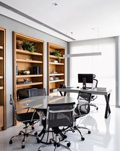 an office with glass desks and wooden shelves