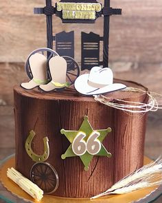 a birthday cake with cowboy hats and decorations on it's top tier, sitting on a glass plate