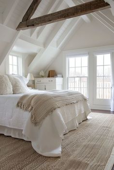 an attic bedroom with white bedding and beige rugs on the carpeted floor