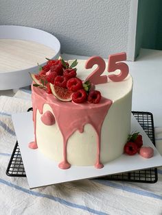 a white cake with pink icing and berries on top