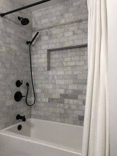 a white bath tub sitting under a window next to a shower head and faucet