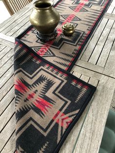 a table with two rugs on it and a vase sitting on top of it