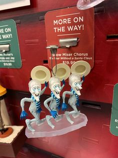 three cartoon figures are on display in front of a vending machine for more on the way