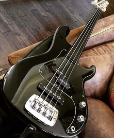 a black bass guitar sitting on top of a couch