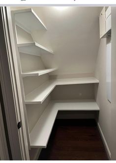 an empty walk in closet with white shelves