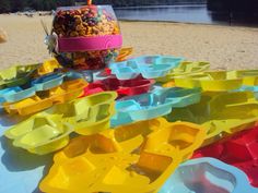 there are many plastic bowls on the table at the beach and one is filled with candy