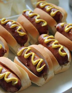 several hot dogs with mustard on them sitting on a plate