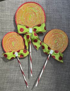 three lollipops with green and red designs on them sitting on a gray surface