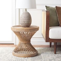 a wicker table with a lamp next to it on a rug in front of a chair