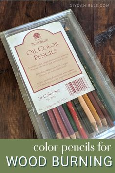 the color pencils for wood burning are in a clear plastic box on a wooden table