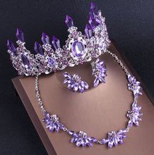 a purple tiara and necklace on top of a brown box next to a pair of earrings