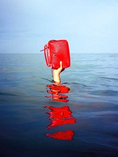 a hand holding a red object in the water