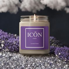 a candle that is sitting on some kind of glittery table cloth with purple flowers in the background