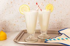 two glasses filled with lemonade sitting on top of a metal tray