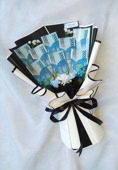 a bouquet of money wrapped in black and white ribbon on top of a white sheet