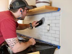 a man is painting the backs of a stove with white tiles and black grout