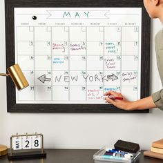 a woman is writing on a calendar board