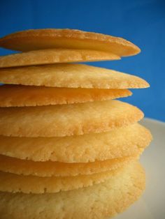 a stack of yellow cookies sitting on top of a white plate next to a blue wall