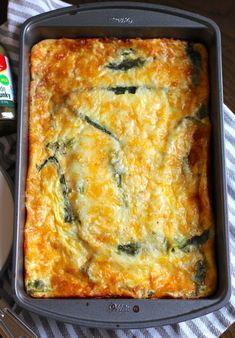 a casserole dish with cheese and spinach in it next to a bottle of ketchup