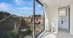 a bathroom with a large window looking out onto the street below and houses in the distance