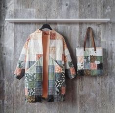 two bags hanging on a wall next to a patchwork jacket and purse with an orange lining