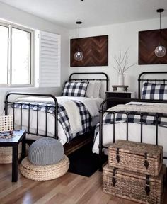 two beds in a room with wooden floors and white walls, one is black and the other has plaid bedding