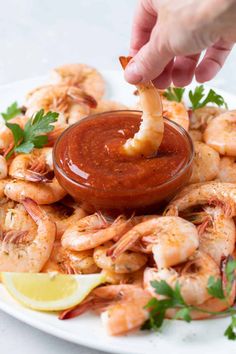 a person dipping sauce onto shrimp on a plate