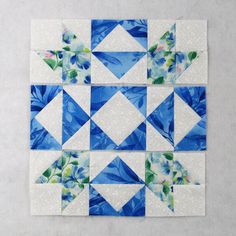 a blue and white patchwork quilt with flowers on the front, one block in the middle