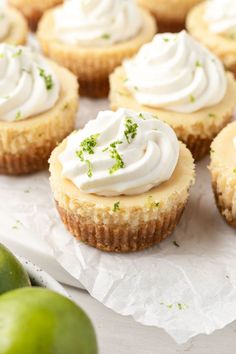 small cupcakes with white frosting and green apples in the background on wax paper