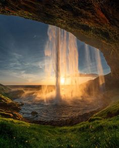 the sun is shining through an opening in a cave with water coming out from it