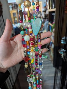 a hand is holding a multi - colored beaded necklace with heart shaped pendants