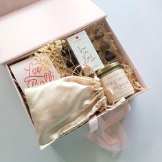 an open box with some items in it on a white table and a pink ribbon