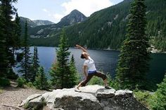 a man standing on top of a rock next to a lake