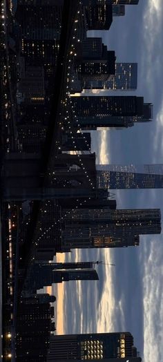 the city skyline is lit up at night, with clouds in the sky behind it