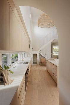 a kitchen with white counter tops and wooden cabinets next to an arched doorway that leads into the living room