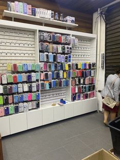 a woman looking at cell phones on display in a store with people standing near by