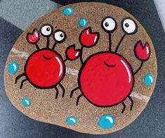 a painted rock with two red crabs on it's face and one has eyes