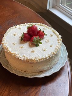 a white cake with three strawberries on top