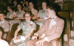 an old photo of some people sitting in chairs and one is wearing a bow tie