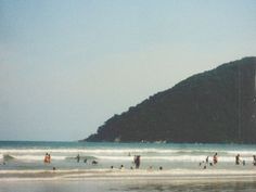 many people are standing in the water at the beach