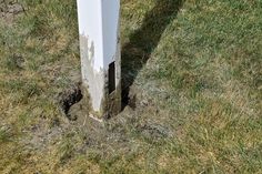 a hole in the ground that has been dug into by a white pole with grass growing around it